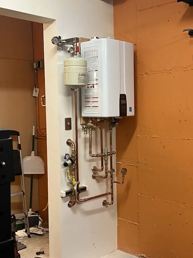 Plumbing technician inspecting water heater connections in Howard